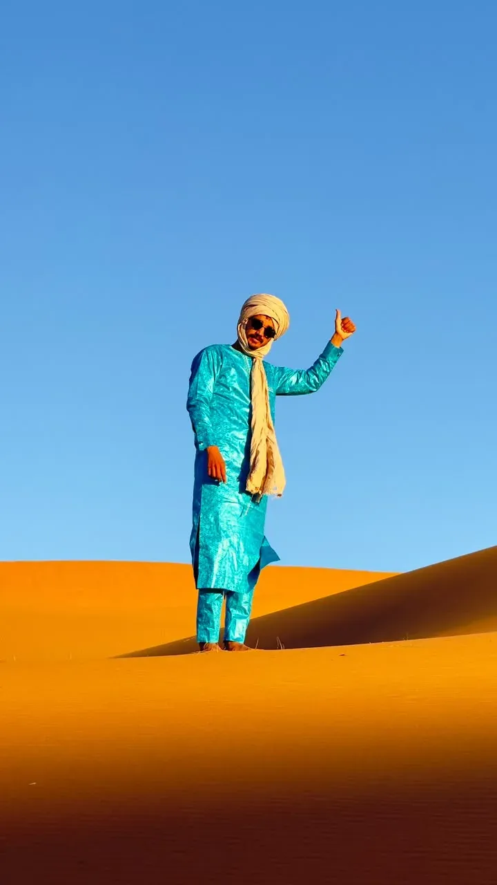 Mohamed gives a thumbs-up from a sand dune